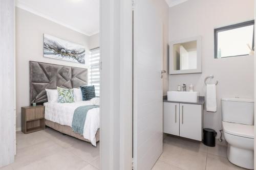 a white bedroom with a bed and a sink at Zoe Lodge in Midrand