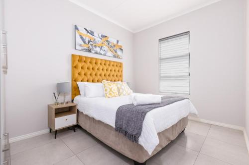 a bedroom with a large bed with a yellow headboard at Zoe Lodge in Midrand