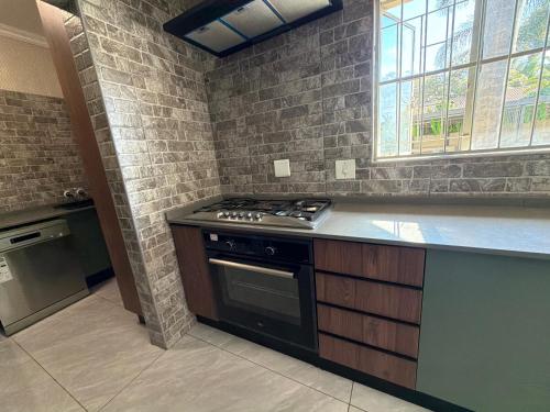 a kitchen with a stove and a stone wall at No 80 At Erasmus in Polokwane