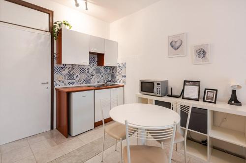 a kitchen with a white table and a white refrigerator at Beachfront Studio Free Parking-Pool 50m from Sea in Chioggia