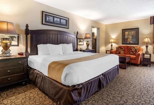 a hotel room with a large bed and a chair at Quality Inn & Suites Escanaba North in Escanaba