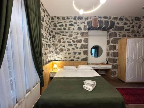 a bedroom with a bed and a stone wall at Kremlin 1908 Hotel in Kars