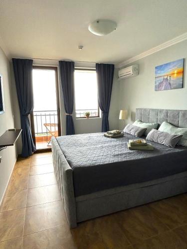 a bedroom with a large bed and two windows at Panorama Sea View in Sveti Vlas