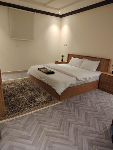 a bedroom with a large bed and a rug at Sukoon Apartment شقة سكون 2 in Buraydah