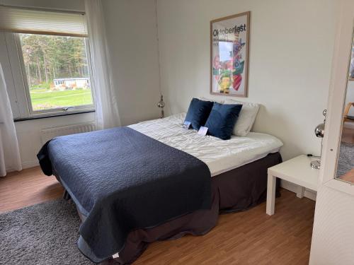 a bedroom with a bed with blue sheets and a window at Hällestrand Vandrarhem - Lägenhet "Laxen" in Strömstad