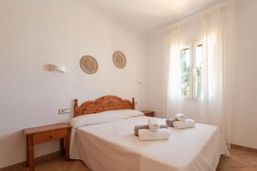 a white bedroom with two towels on a bed at V155 Villa Llebeig in Son Bou