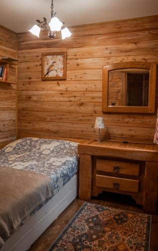 a bedroom with a bed and a wooden wall at Podlaska Chatka Dziadka in Ciwoniuki