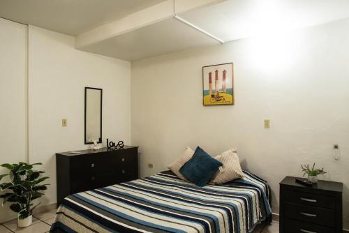 a bedroom with a bed with a striped blanket at Estudio #1 a 10 min del malecon in La Paz