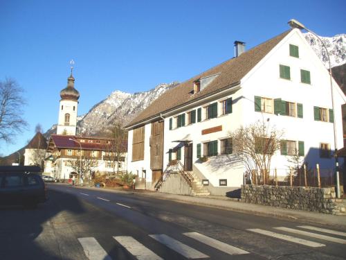 a white building with a clock tower on a street at Gruppenhaus Braz in Innerbraz