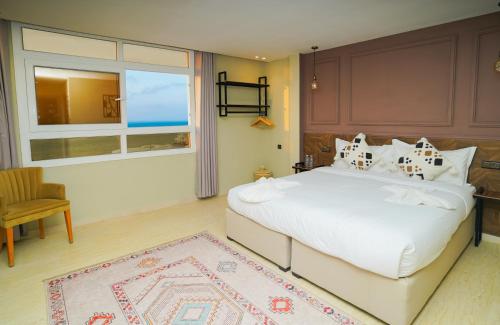 a bedroom with a large white bed and a window at Singular Hotel, SH Dakhla in Dakhla