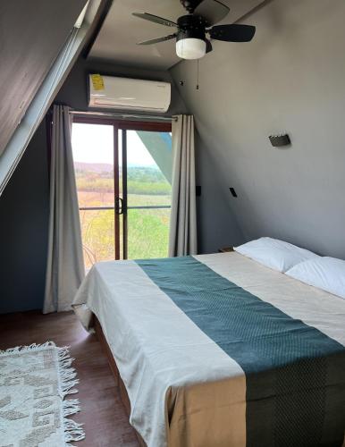 a bedroom with a bed with a ceiling fan and a window at Estancia las Jacarandas Cabañas in San Gabriel Etla