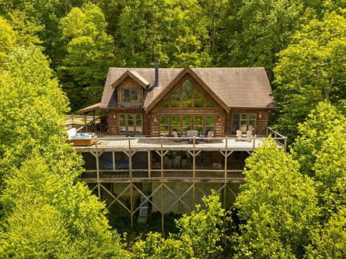 a log house on a dock in the middle of trees at Cucumber Tree Lodge in Banner Elk
