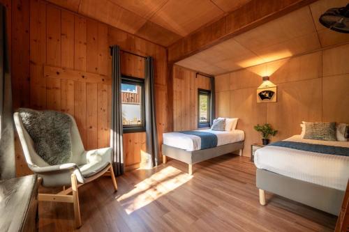 a bedroom with two beds and a chair and a window at Hooting Owl private ski chalet in Niseko