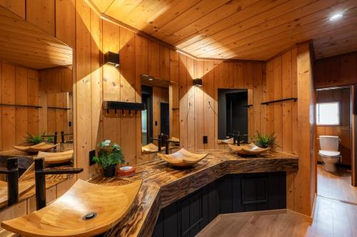 a bathroom with three sinks in a wooden wall at Hooting Owl private ski chalet in Niseko
