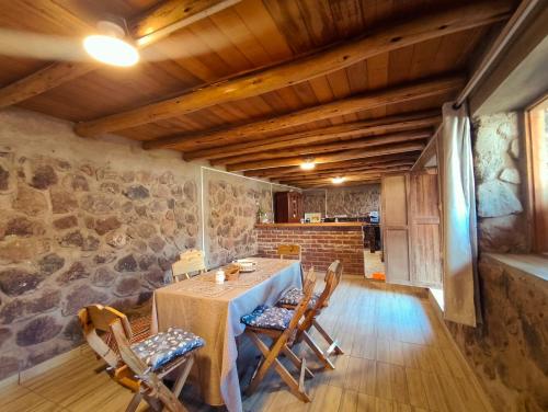 a dining room with a table and chairs and a stone wall at Casa Rumiwillka in Urubamba