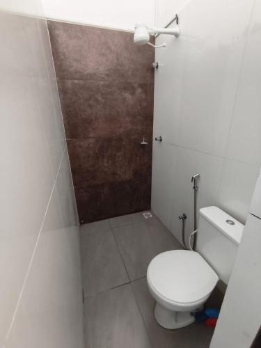 a bathroom with a white toilet and a brown door at Lar Doce Lar Realizando Sono suíte1 in Arcos