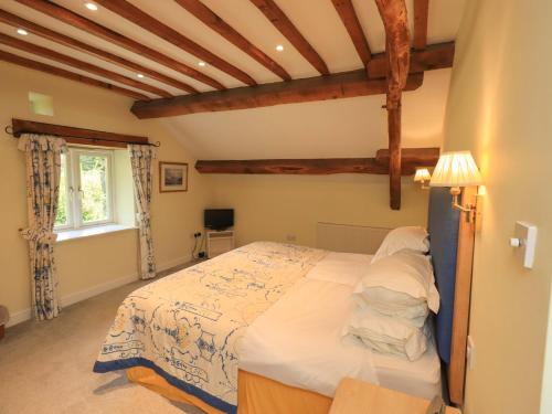 a bedroom with a bed in a room with wooden beams at Pheasant Cottage in Grange Over Sands