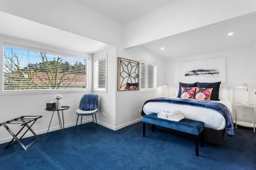 a bedroom with a bed and a chair and two windows at Coromandel Town Harbourside Cottage Luxury Accommodation in Coromandel Town