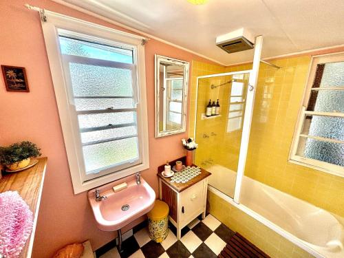 a bathroom with a pink sink and a bath tub at River Cottage on Cherry - Pet Friendly in Evans Head