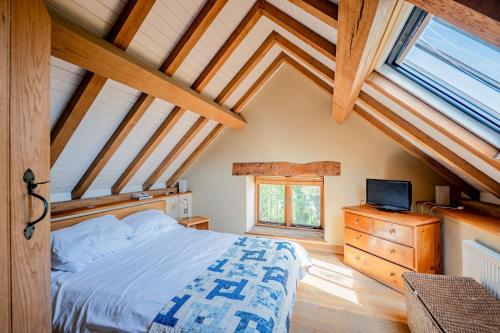 a bedroom with a bed and a tv on a dresser at Cosy Barn Conversion with Patio & Private Parking in Burrington