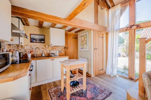 a kitchen with white cabinets and a large window at Cosy Barn Conversion with Patio & Private Parking in Burrington