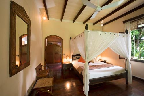 a bedroom with a canopy bed and a mirror at Auberge de Saint Aubin in LʼUnion