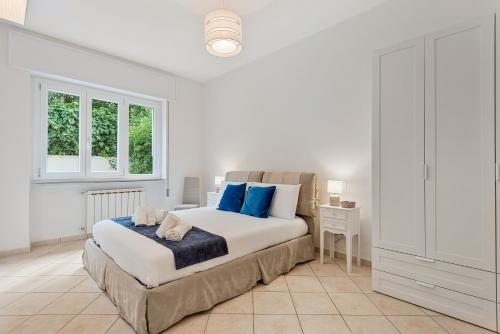 a white bedroom with a large bed with blue pillows at GOLDEN LUXE - Sunset by the Sea in Lido di Camaiore