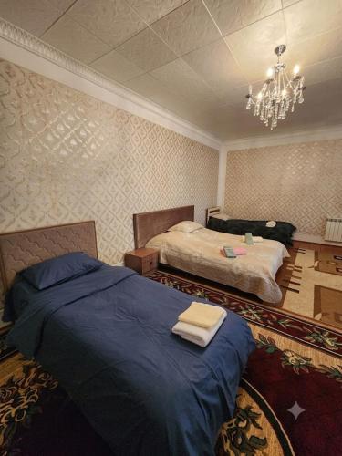 a bedroom with two beds and a chandelier at Sheki Garden Guest House in Sheki