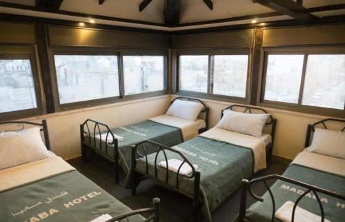 ein Zimmer mit drei Etagenbetten und Fenstern in der Unterkunft Student House in Madaba
