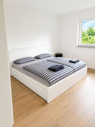 a white bedroom with a bed with black and white stripes at ILA vacation home Memmingen in Memmingen