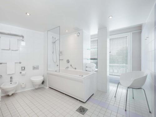 a white bathroom with a tub and a toilet at ibis Styles Tallinn in Tallinn