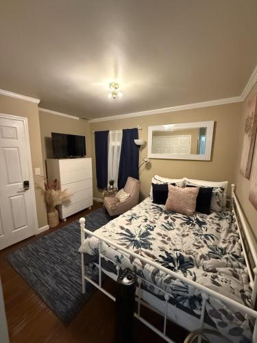 a bedroom with a bed and a chair and a television at The Haven at Mariama House in Upper Marlboro