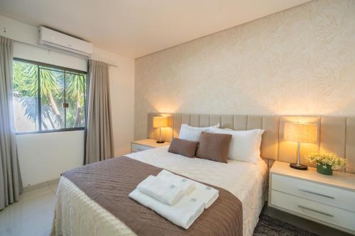a bedroom with a bed with two lamps and a window at Casa de Campo Mimosa Flor Refugio Exclusivo Proximo Cataratas e Aeroporto IGU Piscina Privativa 12 Hóspedes in Foz do Iguaçu
