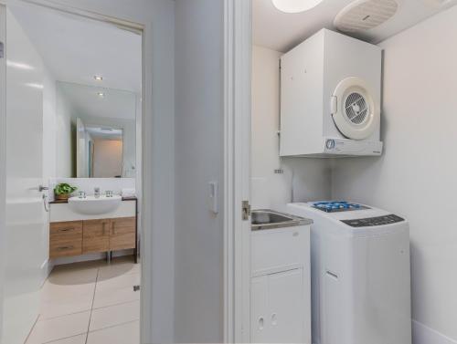 a white kitchen with a sink and a washing machine at Drift North Beachfront Apartments - Private Apartments in Kingscliff