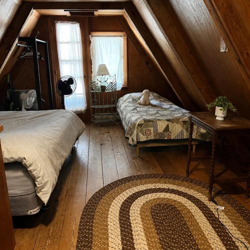 a attic room with two beds and a rug at Adorable Aframe in the White Mountains in Conway