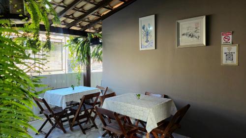 two tables and chairs in a room with plants at Pousada Canto das Samambaias in Capitólio