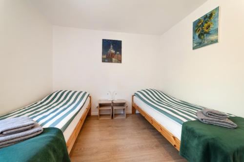 two twin beds in a room with a table at Pokój - Nad Zatoką in Jastarnia