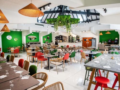 a restaurant with tables and chairs and green walls at Ibis Styles Cayenne Centre Amazonia in Cayenne