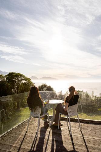 two women sitting at a table on a deck at Expansive Views, Spacious, Large Yard - KK24113 in Kaikoura