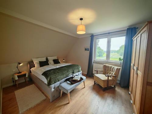 a bedroom with a bed and a chair and a window at Green Lake House in Petershagen