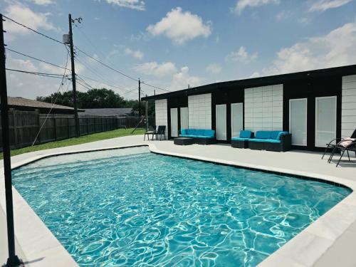 a swimming pool with blue chairs in a backyard at Alma House in Corpus Christi