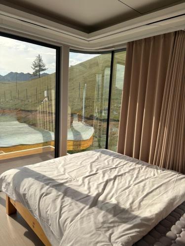 a bedroom with a bed and a large window at Bayalag Resort in Yoliin Hural
