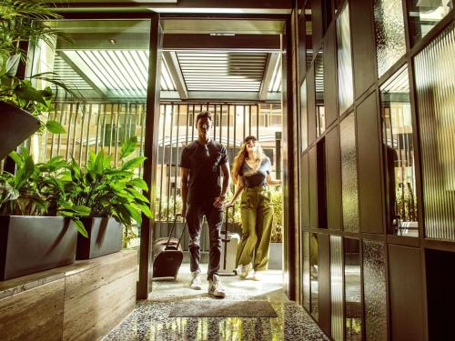 a man and a woman walking through a building at Number 11 St Julian's Malta - Handwritten Collection in St. Julianʼs