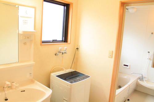 a bathroom with a sink and a toilet and a window at ヴィラルミエール in Yamanakako