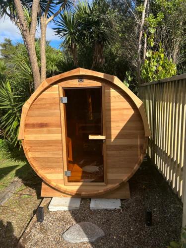 a small wooden dog house sitting in a yard at Seagreen Bach Family Comfort and ease in Raglan