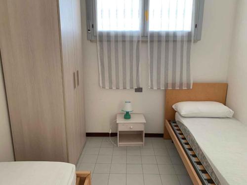 a small room with two beds and a window at Apartment with Pool in Rosolina Mare 57971 in Rosolina Mare
