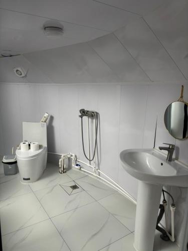 a white bathroom with a sink and a toilet at Bayalag Resort in Yoliin Hural
