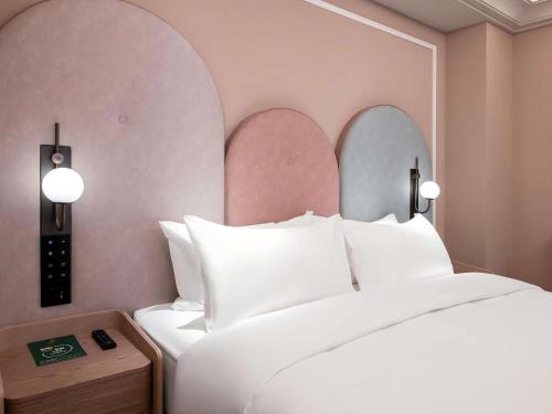 a bedroom with a large white bed with two mirrors at Mercure Chengdu Longtan in Chengdu