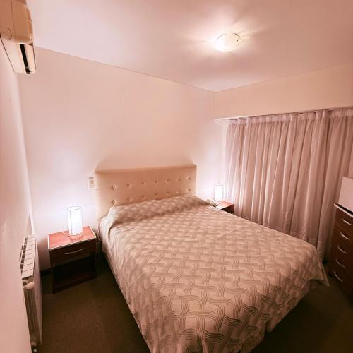 a small bedroom with a bed and two night stands at Hotel Riviera in Las Grutas