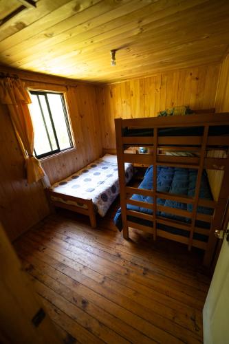 a bedroom with two bunk beds in a wooden cabin at Rio liucura cabañas in Collentañe